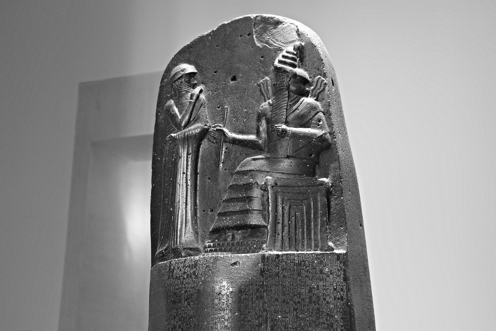 The top of the Code of Hammurabi stele in the Louvre: a king stands before a seated god, above columns of carved law